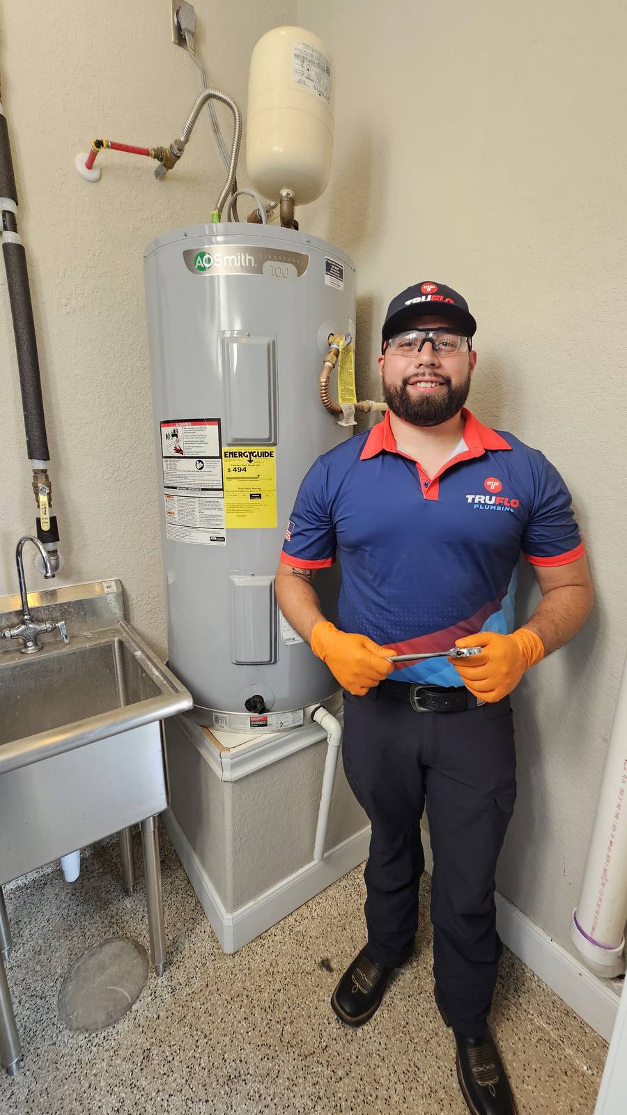 TruFlo master plumber smiling beside a freshly installed water heater